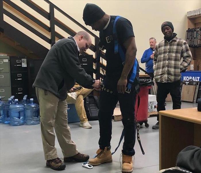 Two men putting on a safety harness